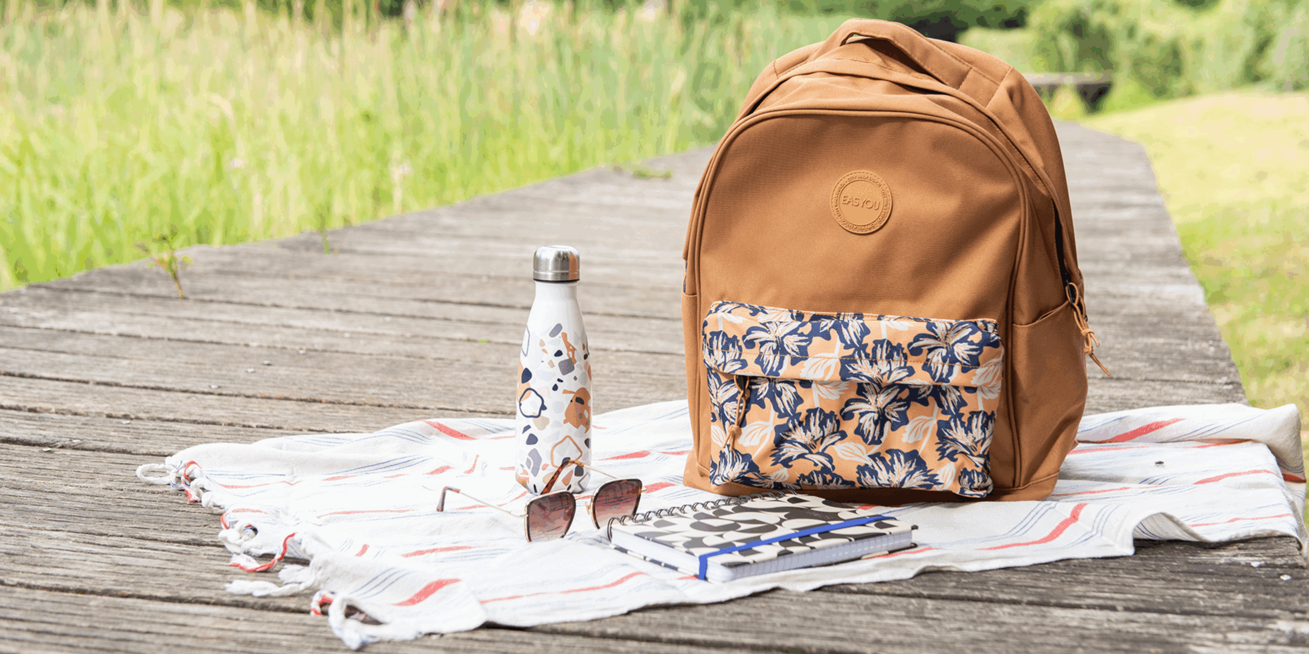 sac à dos marron avec une pochette à fleur sur un ponton